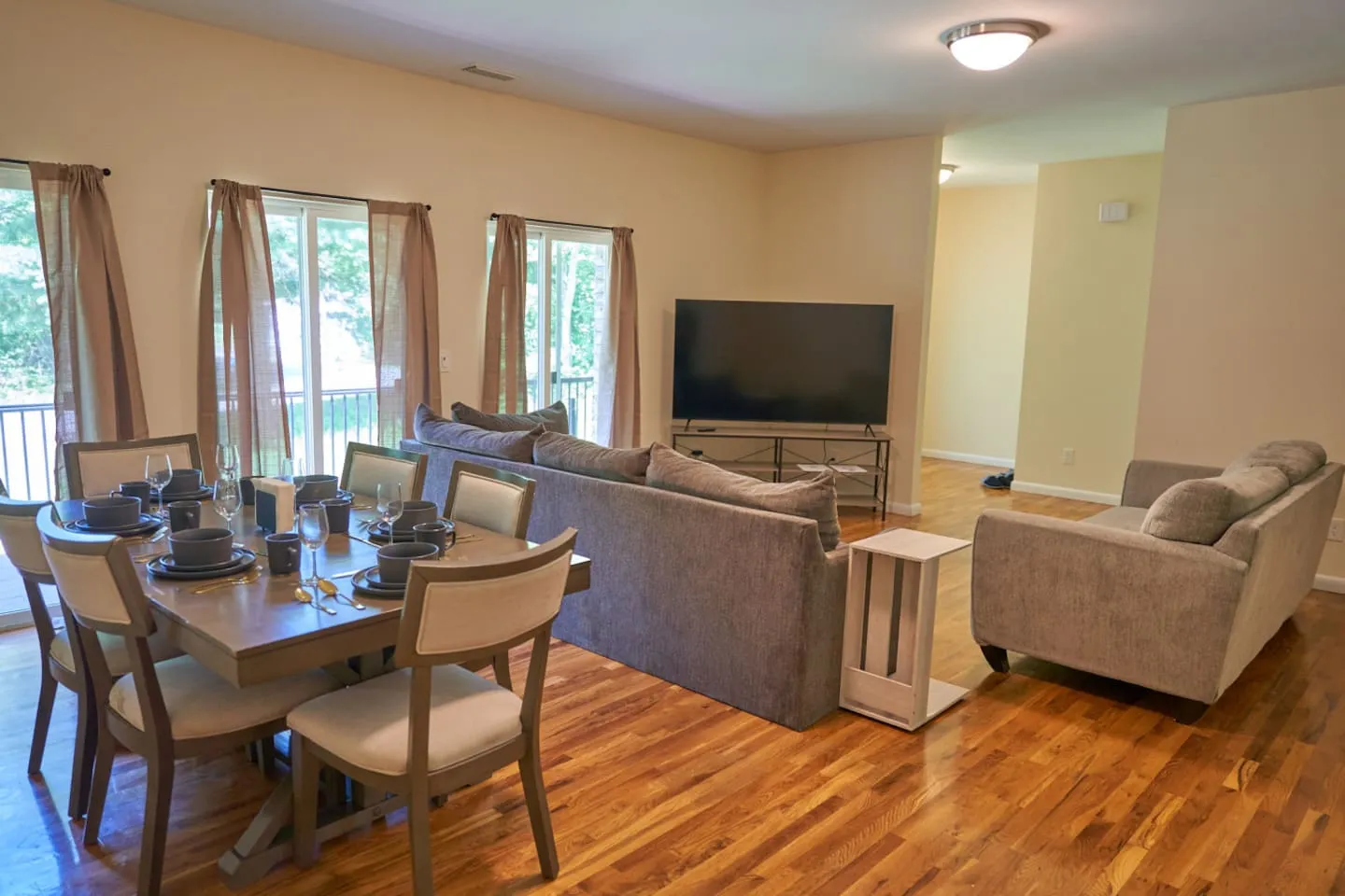 Open-plan living and dining room with hardwood floors and a wall of windows